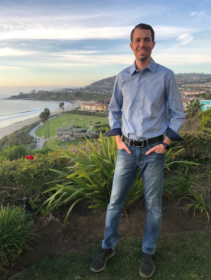 Keith Brown standing above a beach and coastline near sunset