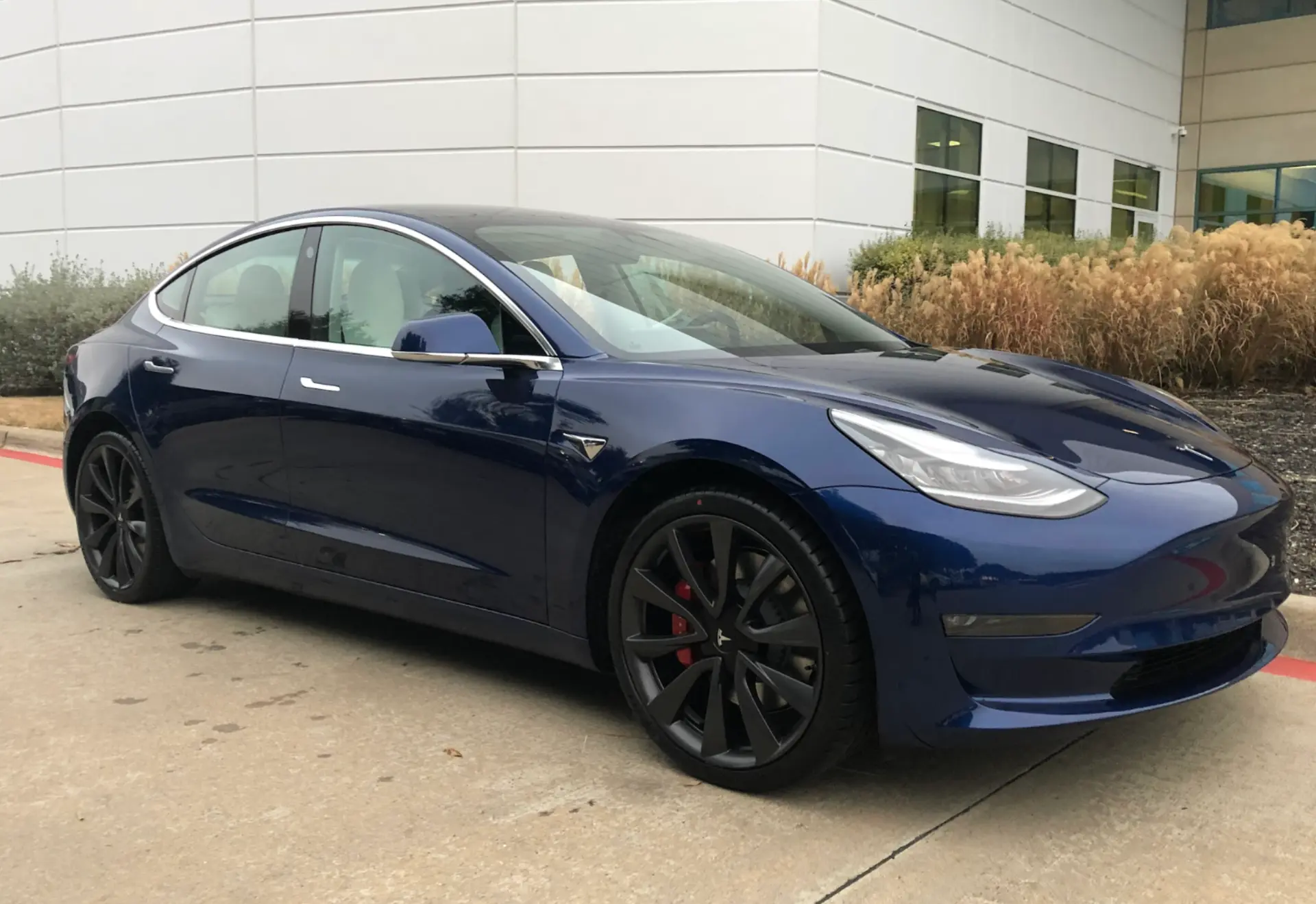 Keith Brown's blue Tesla Model 3 parked outside an office building
