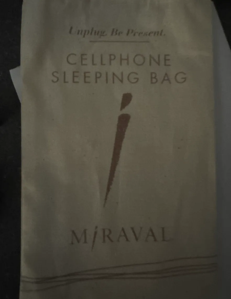 A cream cotton pouch printed with the words Unplug. Be Present., Cellphone Sleeping Bag and the Miraval logo