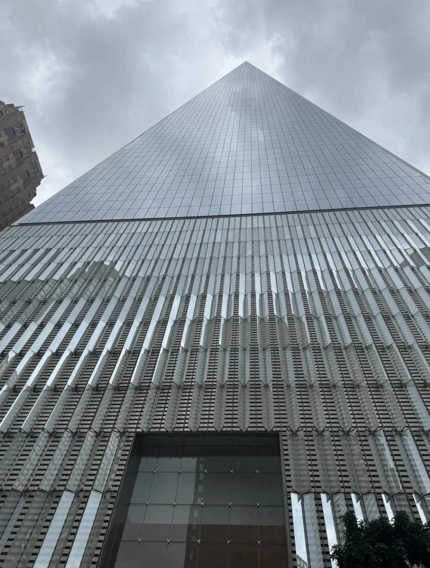 Looking straight up the glass face of One World Trade Center from the street on a cloudy day