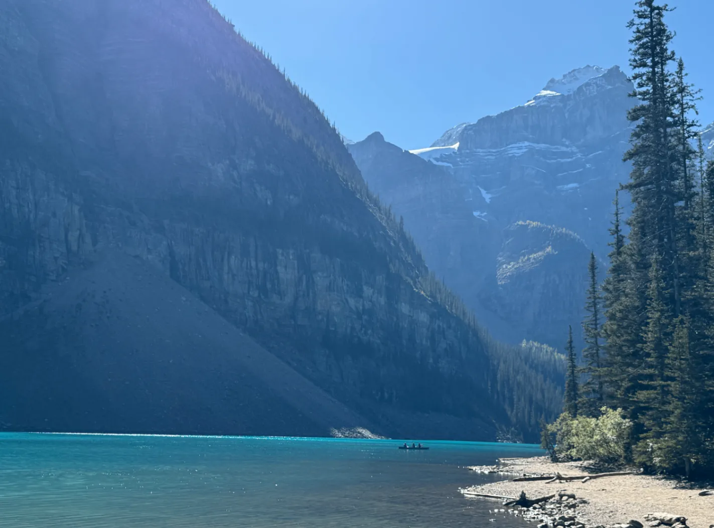 Moraine Lake in Banff National Park: turquoise water, a canoe in the distance, steep mountain walls and pine trees on the shore