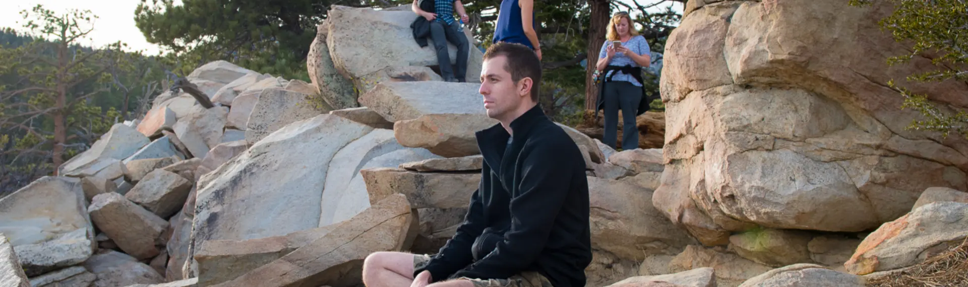 Keith Brown sitting quietly on granite boulders in the mountains at golden hour