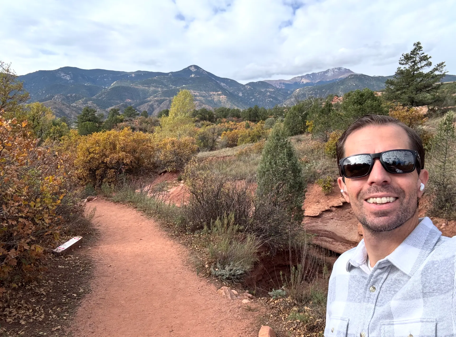 Keith Brown smiling on a red dirt trail at Garden of the Gods in Colorado Springs, with Pikes Peak behind him